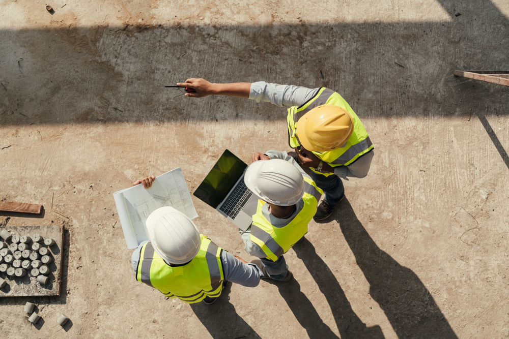 Top view, Team engineer building inspection use tablet computer and blueprint working at construction site. Civil Engineer, Contractor and Architect discussing in construction site