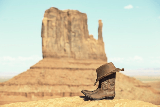 Boots and hat in front of monument valley