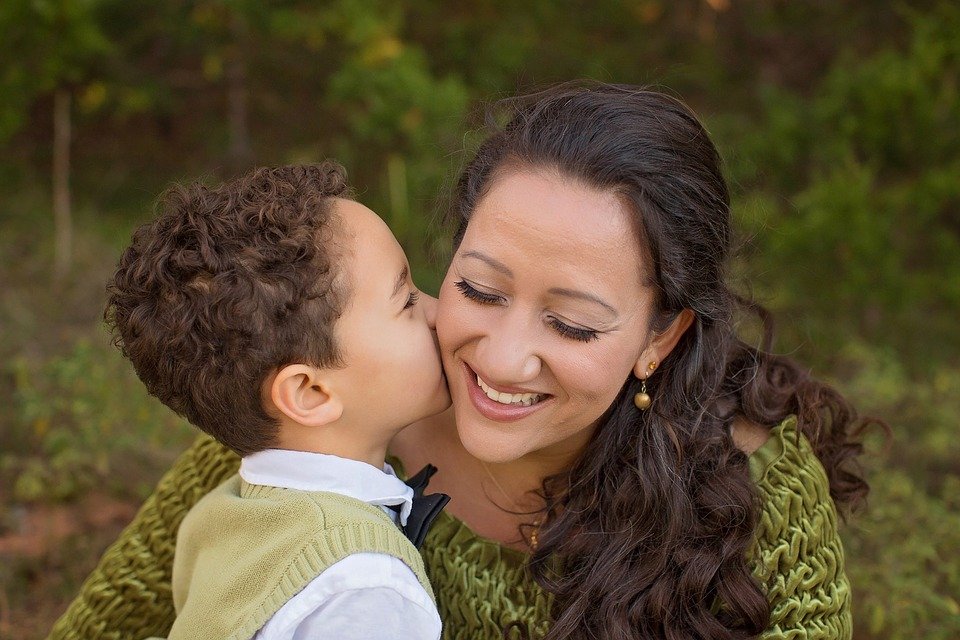 A young boy kissing his mother on the cheek