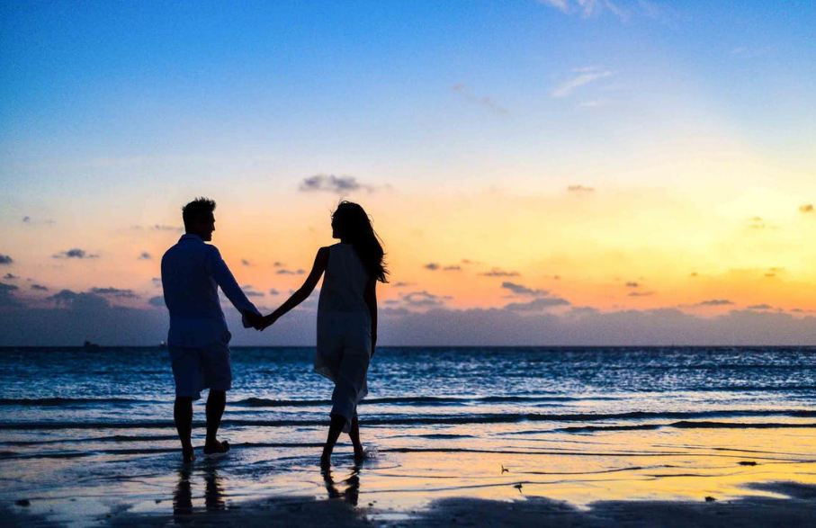 man-and-woman-holding-hands-walking-on-seashore-during-sunrise
