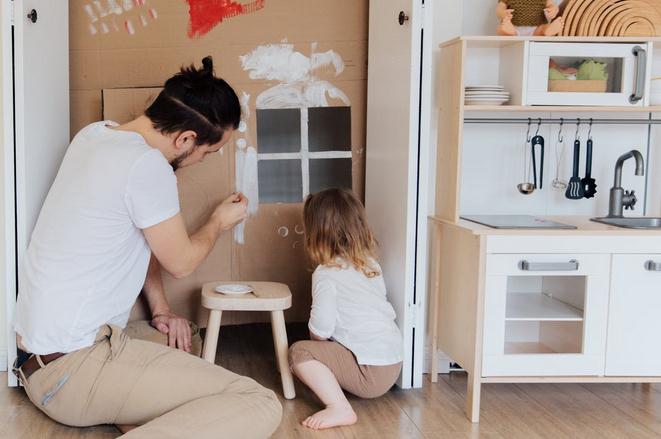 Father painting cardboard with kid