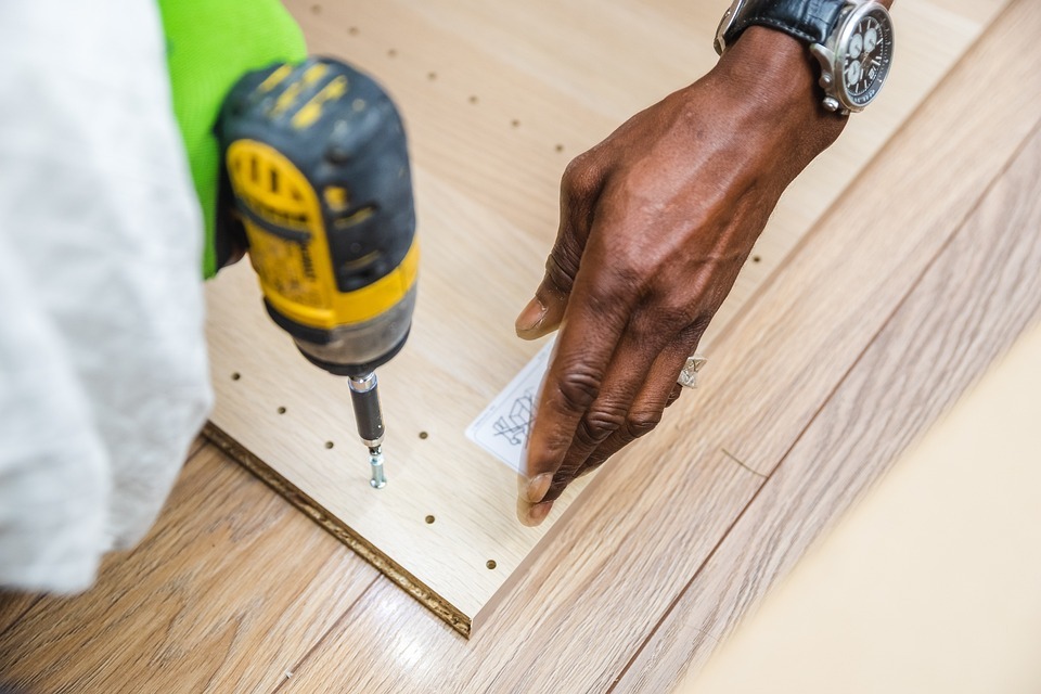 Handyman using yellow cordless drill to assemble furniture